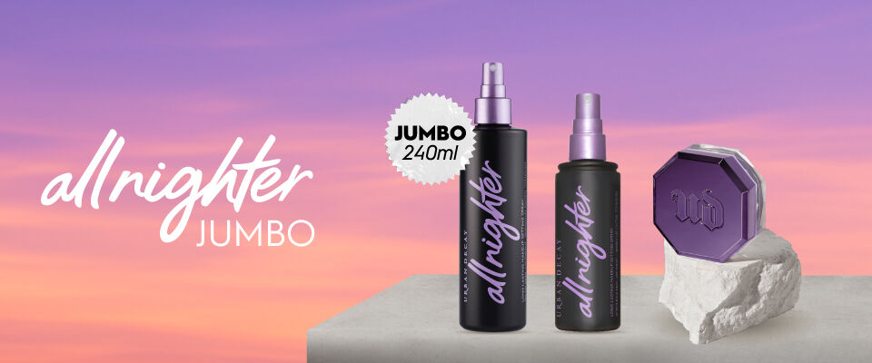 Urban Decay All Nighter Jumbo. Dos sprays fijadores y un compacto purpura sobre un fondo de atardecer
